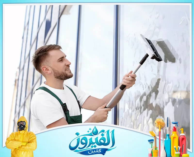 تنظيف لوبي العمائر في القطيف 0562185880 شركة الفيروز عامل تنظيف بملابس العمل يمسح الزجاج بممسحة طويلة.