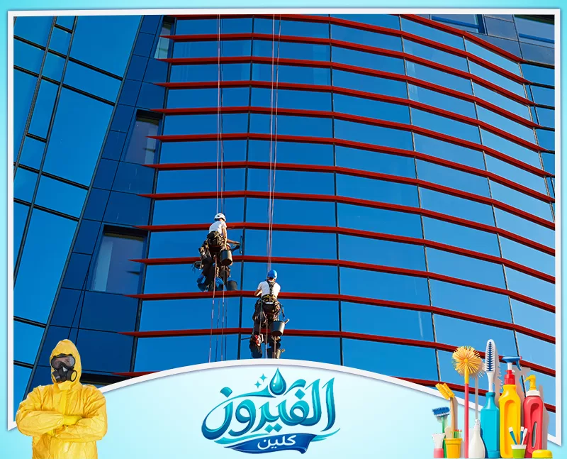 تنظيف سلالم العمائر في القطيف 0562185880 شركة الفيروز عمال تنظيف نوافذ معلقون بحبال على واجهة زجاجية زرقاء حديثة.