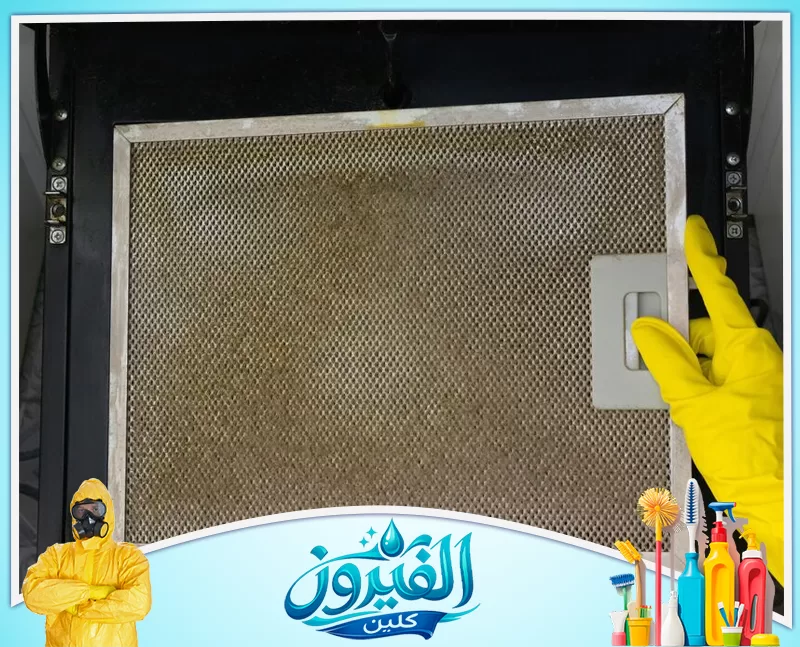 تنظيف المراوح ووحدات الشفط في رأس تنورة 0562185880 شركة الفيروز يد بقفاز أصفر تمسك مرشح شفاط مطبخ معدني متسخ ومغطى بالدهون استعداداً لتنظيفه.
