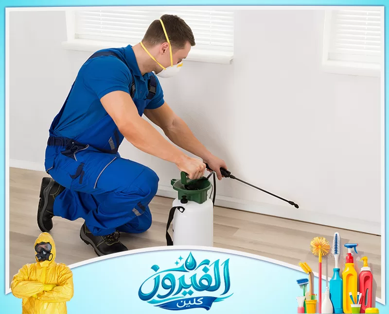 مكافحة الصراصير في الجبيل 0562185880 شركة الفيروز فني مكافحة يرتدي زيًا أزرق وكمامة، يرش الزوايا السفلية بحرص للقضاء على الآفات وضمان نظافة المنزل وأمانه.