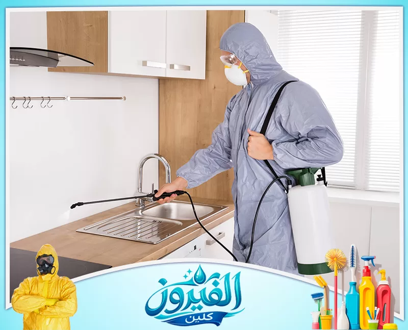 رش مبيدات في الجبيل 0562185880 شركة الفيروز عامل مكافحة حشرات بزي واقٍ وكمامة، يقوم برش المبيدات بدقة داخل مطبخ عصري لضمان بيئة آمنة ونظيفة من الآفات.