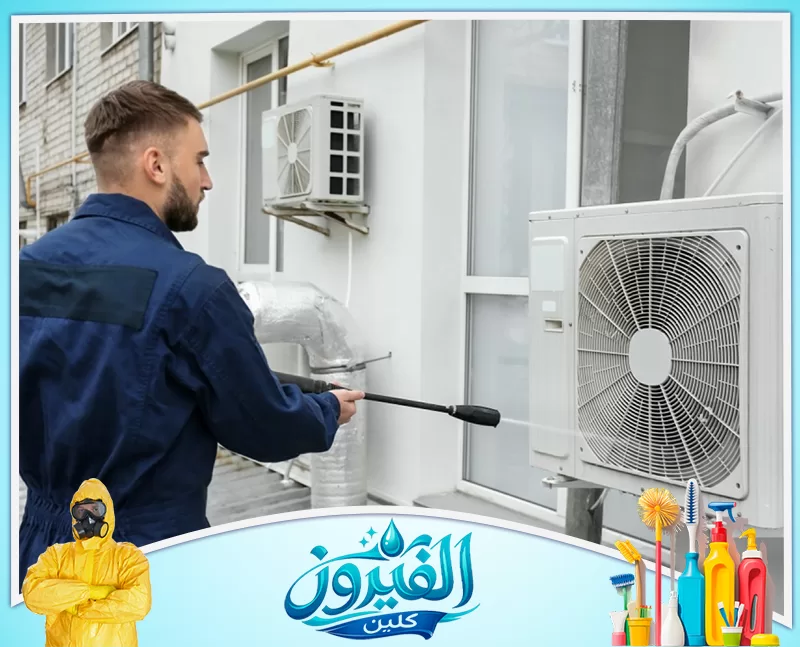 تنظيف مكيفات شباك بالظهران 0562185880 شركة الفيروز فني يرتدي زياً أزرق ينظف وحدة تكييف خارجية بضغط الماء العالي لضمان كفاءة التبريد.