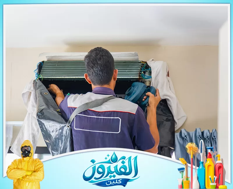 تنظيف مكيفات شباك بالجبيل 0562185880 شركة الفيروز فني تكييف من الخلف ينظف مكيفًا داخليًا مكشوفًا بمسدس نفخ، بوجود أكياس تغطية وأغطية واقية.