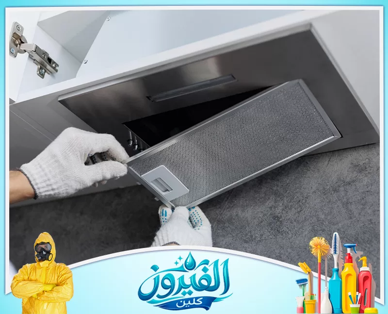 تركيب مكيف شباك بالقطيف 0562185880 شركة الفيروز يد ترتدي قفازات بيضاء تقوم بتركيب أو صيانة فلتر معدني لشفاط مطبخ فضي مدمج داخل خزانة خشبية بيضاء.