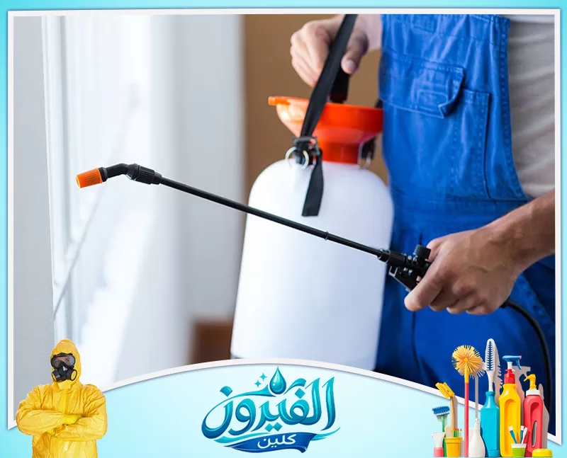 مكافحة البق بالدمام 0562185880 شركة الفيروز عامل بزي أزرق يستخدم بخاخًا لرش زاوية الجدار، يظهر الجزء السفلي من جسمه والبخاخ بوضوح.