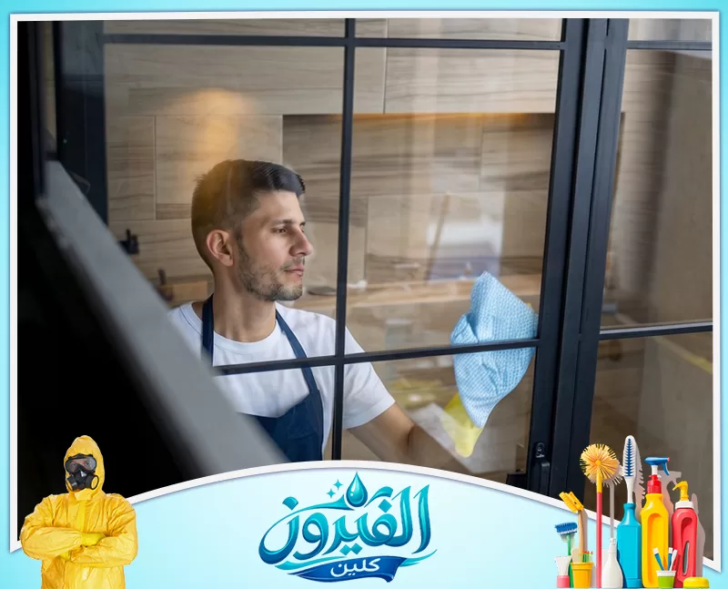 شركة تنظيف زجاج بالدمام 0562185880 شركة الفيروز عامل تنظيف يمسح الزجاج بقطعة قماش، والصورة مناسبة للتعبير عن تنظيف النوافذ والواجهات الزجاجية.